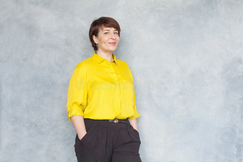 Amistosa mujer de negocios de mediana edad con camisa amarilla sonriendo, retrato