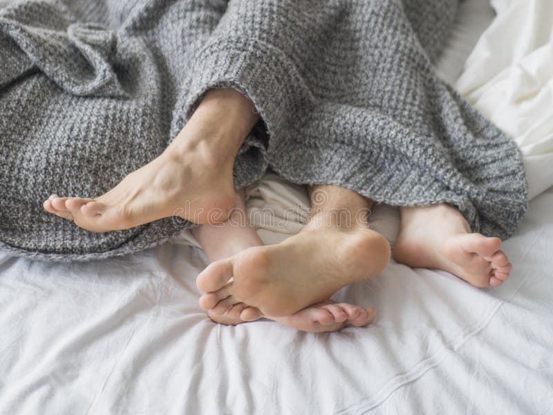 Amor apasionado Pies de un par joven que mintiendo en la cama en la luna de miel Júntese en el amor que duerme debajo de la manta foto de archivo Amor apasionado Pies de un par joven que mintiendo en la cama en la luna de miel Júntese en el amor que duerme debajo de la manta foto de archivo