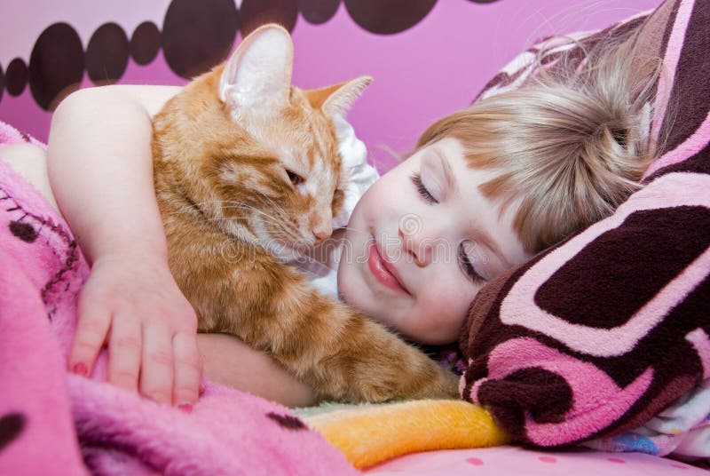 Little girl holding her pet tabby cat in bed. Little girl holding her pet tabby cat in bed.