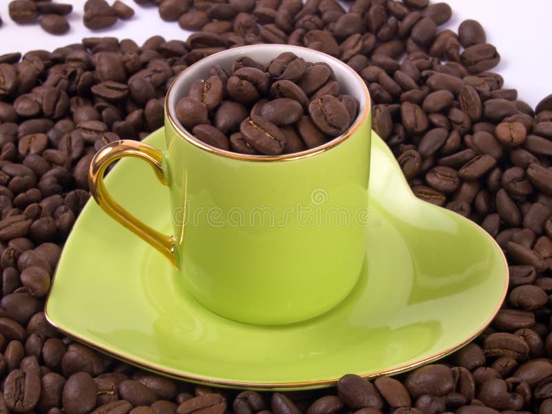 Green cup of coffee sitting in a coffee beans. Green cup of coffee sitting in a coffee beans