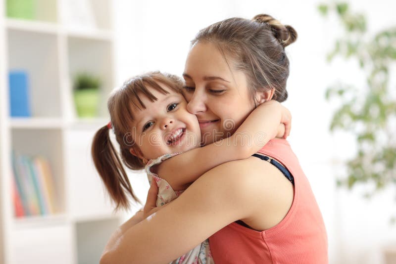 Love and family concept - happy mother and child daughter hugging at home. Love and family concept - happy mother and child daughter hugging at home