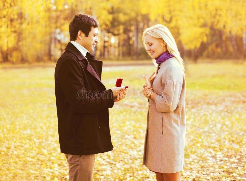 Amore, relazioni, concetto di nozze e di impegno - l'uomo propone una donna per sposare, anello rosso della scatola, giovane copp