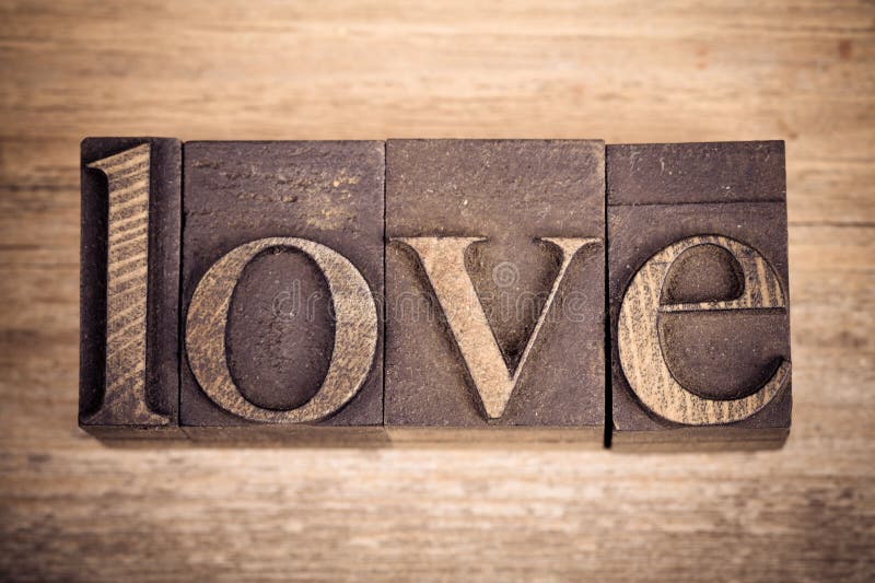 The word LOVE written with vintage printing blocks over old wood background. The word LOVE written with vintage printing blocks over old wood background