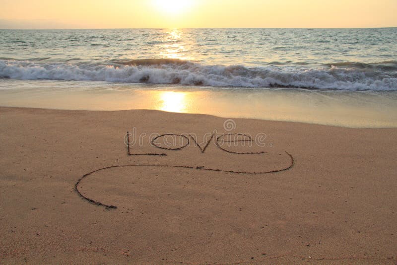 The word Love, handwritten in a sandy beach at sunset. The word Love, handwritten in a sandy beach at sunset.