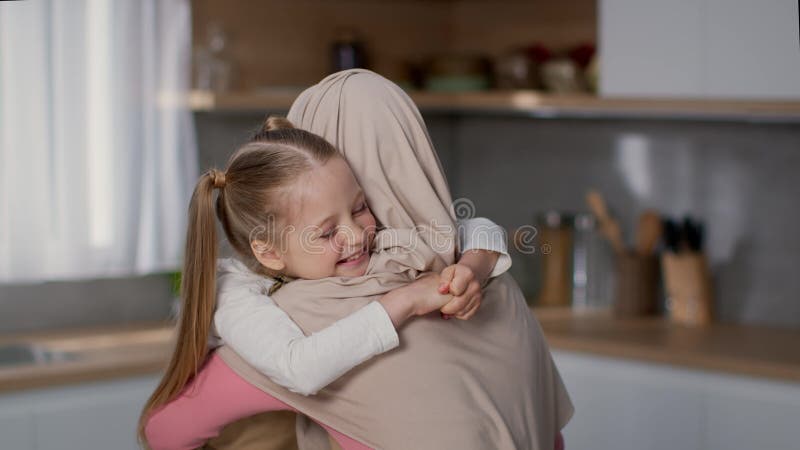 Amour pour enfant sincère. mignonne petite fille heureuse embrassant sa belle mère musulmane à la cuisine ralenti banque de vidéos