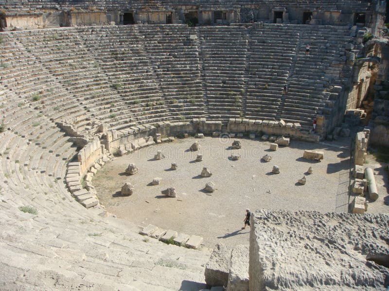 Amphitheater of Myra in Turkey in summer. Roman amphitheater. Sunny day. White color. Travel destination. Archeological area. Culture and story. Half circle with file of steps. Steps of stone. Rocks in the center. Preserved very well. Walking man. Travel destination. Amphitheater of Myra in Turkey in summer. Roman amphitheater. Sunny day. White color. Travel destination. Archeological area. Culture and story. Half circle with file of steps. Steps of stone. Rocks in the center. Preserved very well. Walking man. Travel destination.