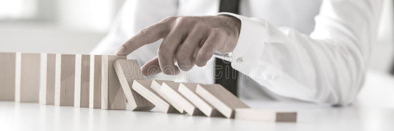 Ampio punto di vista potato di un uomo d'affari che ferma effetto di domino immagini stock libere da diritti Ampio punto di vista potato di un uomo d'affari che ferma effetto di domino immagini stock libere da diritti