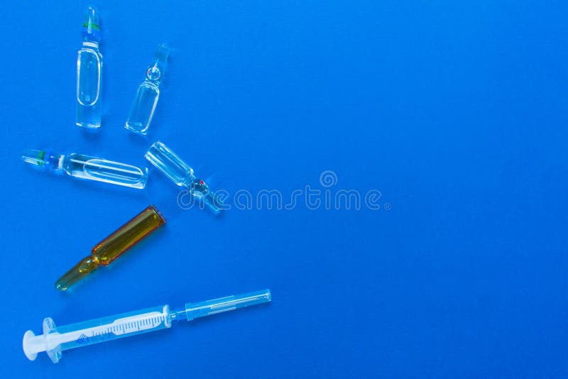 Ampoules and syringe for injection. Medical drugs on a blue background. Flat layout, stock photo Ampoules and syringe for injection. Medical drugs on a blue background. Flat layout, stock photo