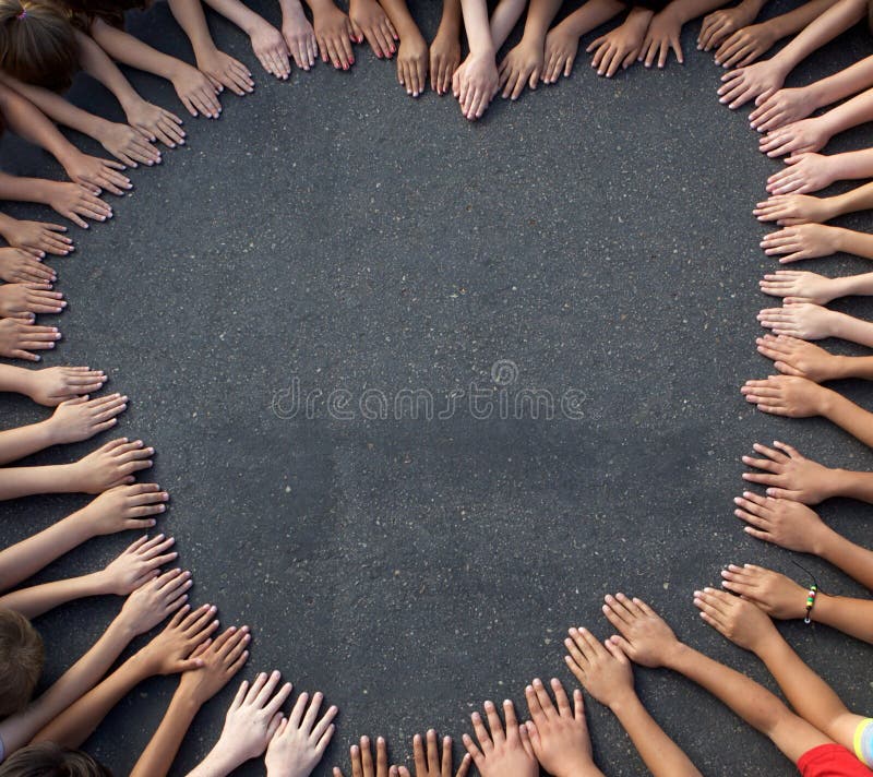 A large group of children's hands coming together on pavement to form the shape of a heart. Shot from above. A large group of children's hands coming together on pavement to form the shape of a heart. Shot from above