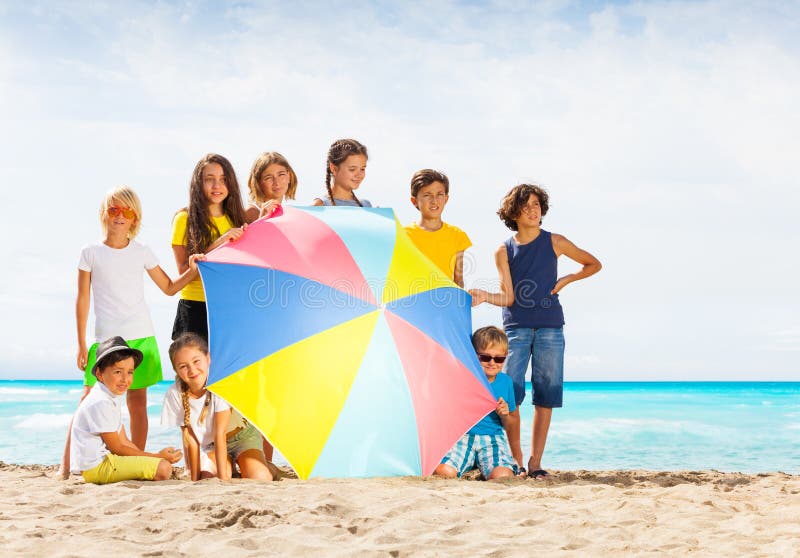 Ampuły grupa dzieciaki za plażowym parasolem zdjęcie stock Ampuły grupa dzieciaki za plażowym parasolem zdjęcie stock