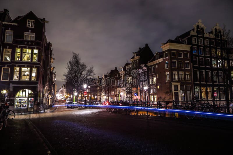 Amsterdam miasta nocy ulicy z różnymi rodzajami rusza się transport & sylwetki passersby zdjęcie stock Amsterdam miasta nocy ulicy z różnymi rodzajami rusza się transport & sylwetki passersby zdjęcie stock