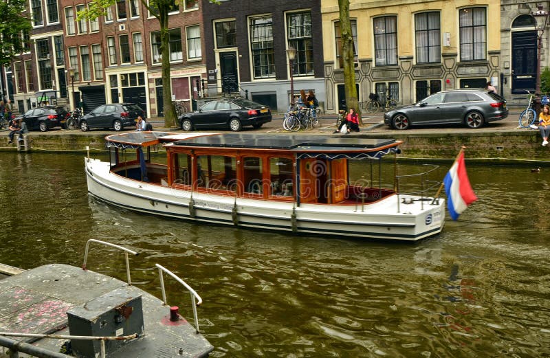Amsterdam, Nederland Augustus 2019 Een boot langs een van de kanalen van het rode lichtdistrict Parkeerauto's en fietsen langs de royalty-vrije stock afbeeldingen Amsterdam, Nederland Augustus 2019 Een boot langs een van de kanalen van het rode lichtdistrict Parkeerauto's en fietsen langs de royalty-vrije stock afbeeldingen