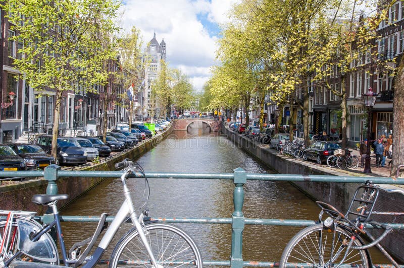 AMSTERDAM NETHERLANDS-APRIL 27: Amsterdam kanal med cyklar på bron och de parkerade bilarna längs banken på April 27,2015 arkivfoton AMSTERDAM NETHERLANDS-APRIL 27: Amsterdam kanal med cyklar på bron och de parkerade bilarna längs banken på April 27,2015 arkivfoton