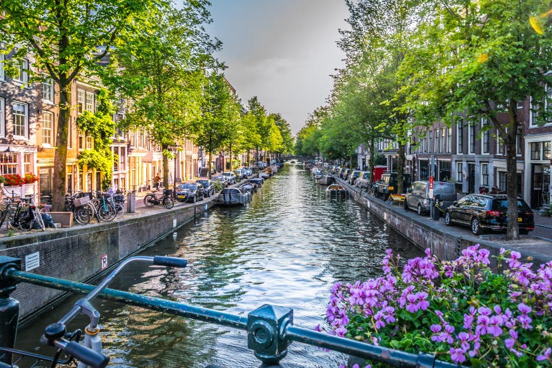 Amsterdam, Netherlands - July 19, 2019: View of one of the canals in Amsterdam from one of the bridges with its flowers