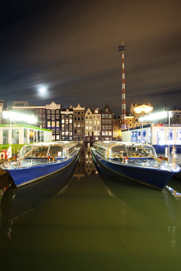 Amsterdam por noche - los barcos acercan a la calle de Damrac foto de archivo libre de regalías