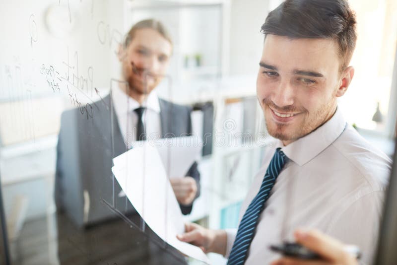 Analyst pointing at data on board stock photos