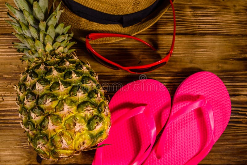 Ananas, cappello di paglia, occhiali da sole e Flip-flop sulla tavola di legno Vacanze di estate Vista superiore immagini stock libere da diritti Ananas, cappello di paglia, occhiali da sole e Flip-flop sulla tavola di legno Vacanze di estate Vista superiore immagini stock libere da diritti