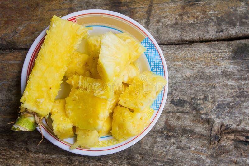 Ananas heerlijke zoete die ui, besnoeiing in stukken in een schotel op een houten lijst op de achtergrond wordt geplaatst royalty-vrije stock foto Ananas heerlijke zoete die ui, besnoeiing in stukken in een schotel op een houten lijst op de achtergrond wordt geplaatst royalty-vrije stock foto
