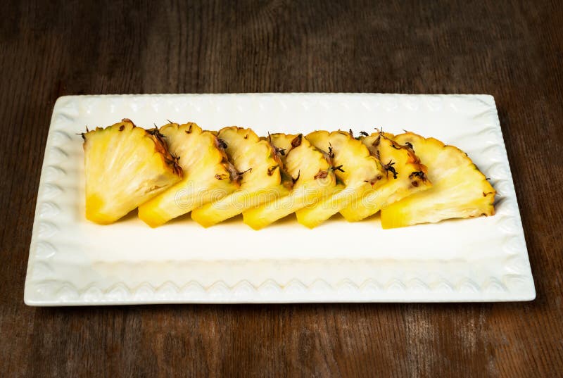 Ananasfruktsnitt i kilar på det sunda mellanmålet plattaför träbakgrund arkivfoto Ananasfruktsnitt i kilar på det sunda mellanmålet plattaför träbakgrund arkivfoto