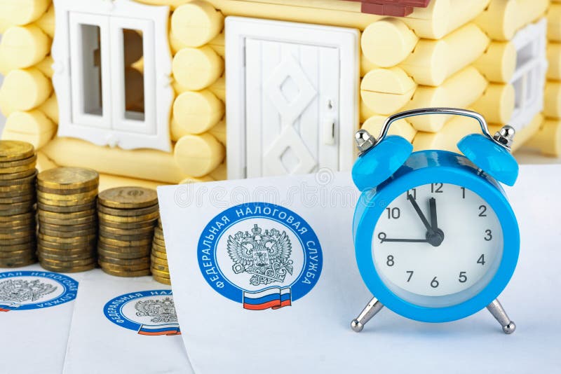 Anapa, Russia - September 3, 2019: Tax notifications, watches, stacks of coins on the background of the house royalty free stock image Anapa, Russia - September 3, 2019: Tax notifications, watches, stacks of coins on the background of the house royalty free stock image