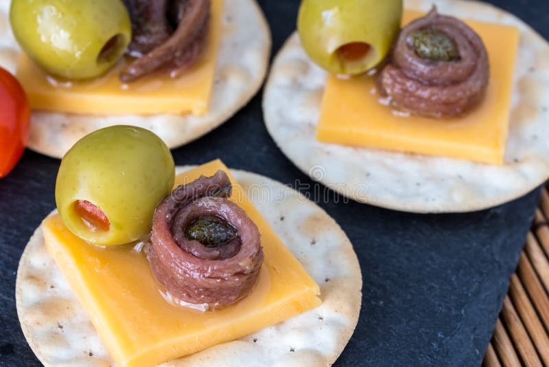 Anchovy on crackers with stuffed olives - Appetizer background w