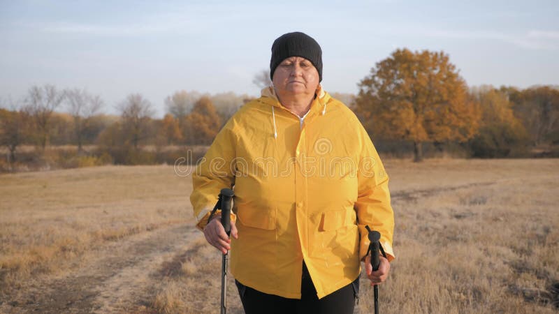 Anciana haciendo caminata nórdica en el bosque de otoño. carrera de senderismo nórdico en el camino del otoño. jubilados sanos