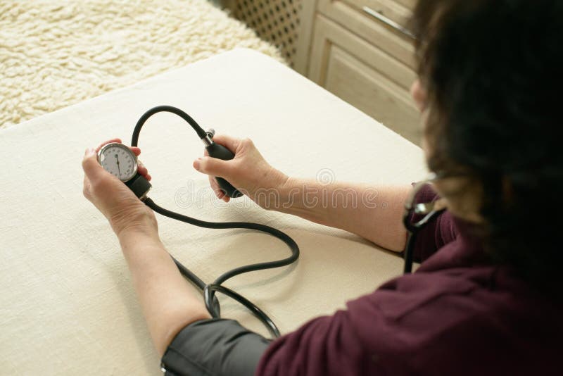 Ancianos Autocontrol De La Presión Arterial Femenina Con Sfigmomanómetro Manual imagenes de archivo