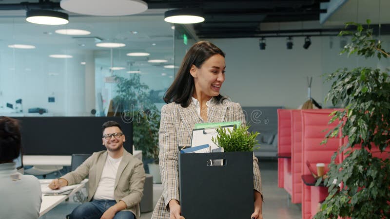 Ancien employé heureux de jeune femme stoppant le travail quittant la partie bureau avec la boîte de choses banque de vidéos