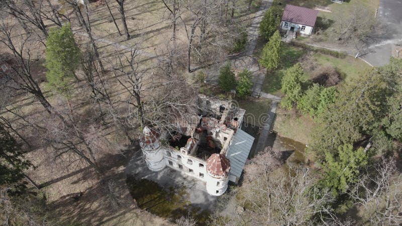 Ancien manoir abandonné vue aérienne. toit cassé. ruines au milieu d'une forêt printanière clips vidéos