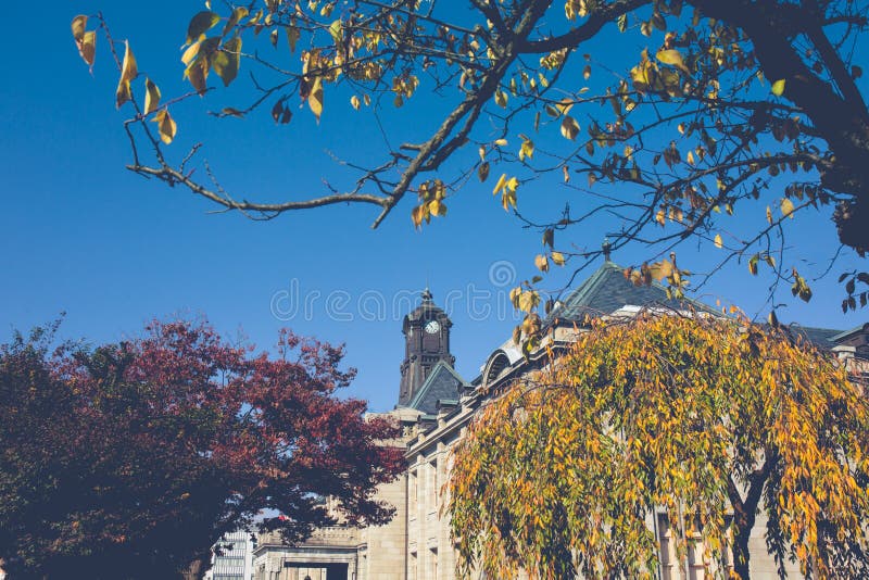 The ancient clock tower on the roof of the old building has red leaves, orange and blue skies. Autumn in Yamagata, Japan,Vintage