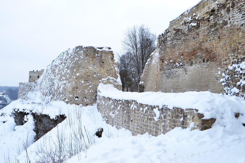 Ancient fortress wall and tower covered with snow, the wall is made of stone and limestone.Russia, Izborsk in winter time.