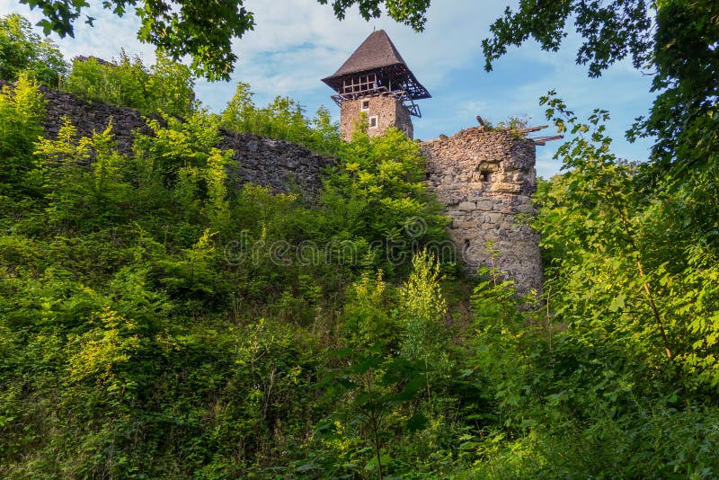 An ancient, partially destroyed fortress lonely stands on top of a green hill stock photo