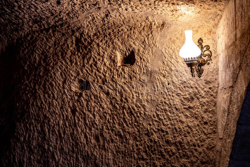 Ancient rough wall in cave with light from lamp in darkness royalty free stock images