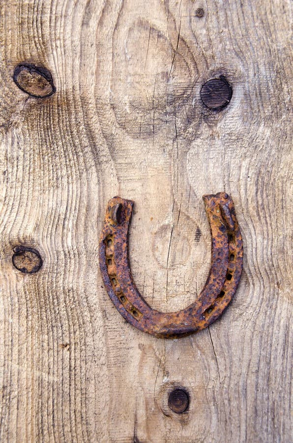 Ancient rusty horseshoe on old wooden plank background stock image