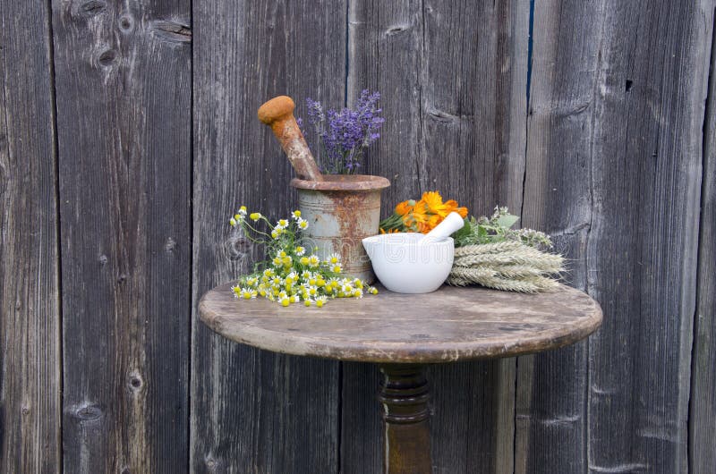 Ancient rusty iron mortar and medical herbs on old wooden table royalty free stock photos