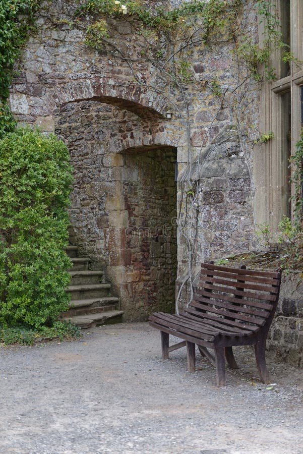 An ancient stone stairway and wooden bench surrounded by a green creeper in Dunster castle, somerset, UK, Europe.