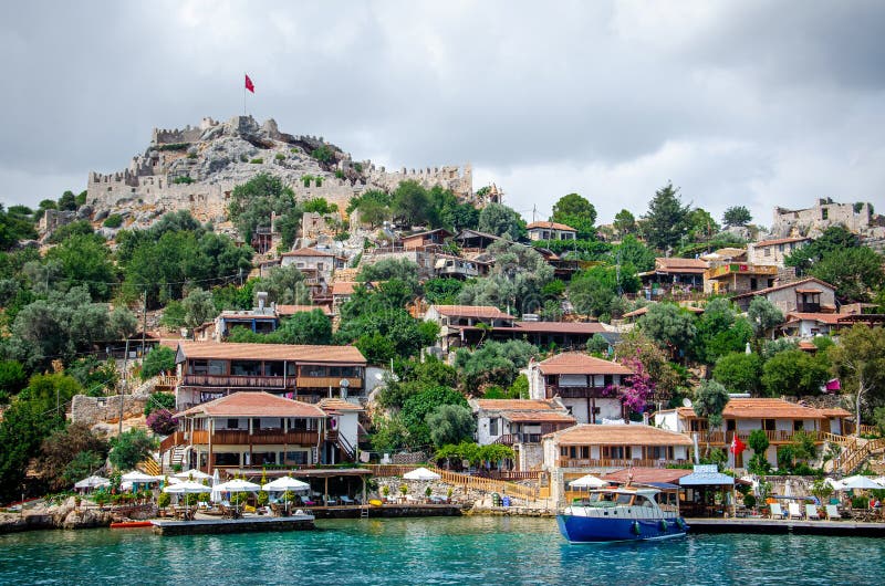 Ancient village of Simena with castle on mountain. Boat dock, beautiful landscape. Sea tour of Lycian underwater city on