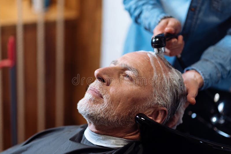 Ancião durante o lavagem de seu cabelo na barbearia imagens de stock royalty free Ancião durante o lavagem de seu cabelo na barbearia imagens de stock royalty free