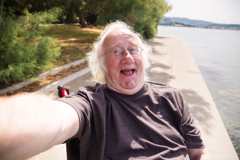 Ancião na cadeira de rodas que toma um Selfie imagens de stock royalty free Ancião na cadeira de rodas que toma um Selfie imagens de stock royalty free