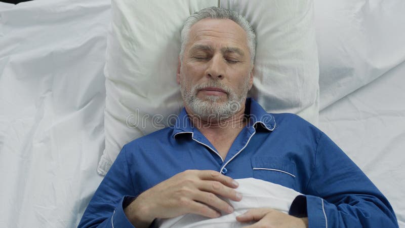 Ancião que aprecia o conforto do sono devido ao colchão e aos descansos ortopédicos