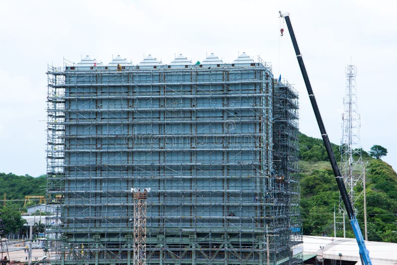 Andamio alrededor del nuevo edificio con la grúa de la elevación con la montaña detrás fotografía de archivo libre de regalías Andamio alrededor del nuevo edificio con la grúa de la elevación con la montaña detrás fotografía de archivo libre de regalías