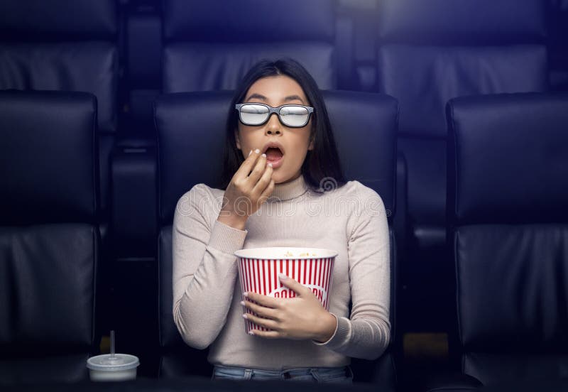 Andare al cinema da solo. donna asiatica spaventata in occhiali 3d che guarda thriller al cinema