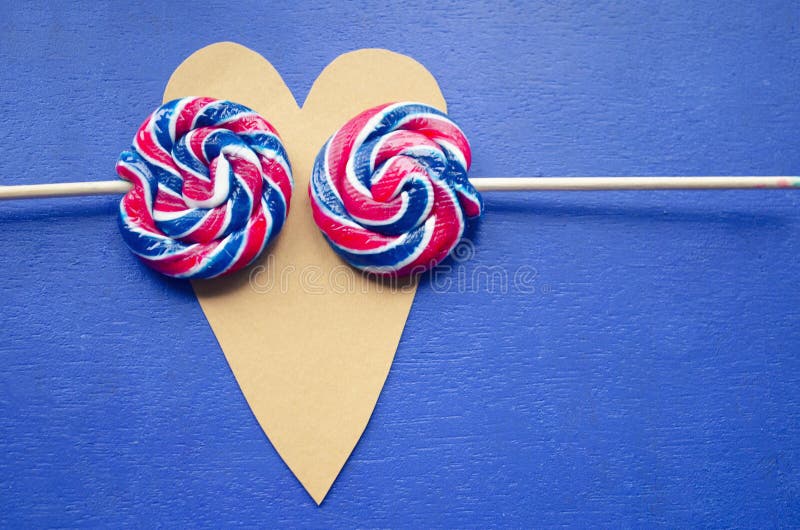 Andy swirl rainbow round two lollipops on heart-shaped. Candy stripes on a stick on blue background. Love concept. February 14. Ho stock image Andy swirl rainbow round two lollipops on heart-shaped. Candy stripes on a stick on blue background. Love concept. February 14. Ho stock image