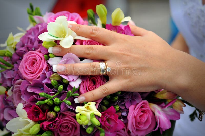 A wedding ring on a finger with flowers. A wedding ring on a finger with flowers