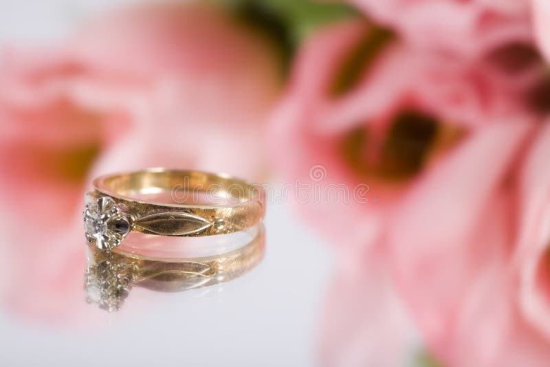 A gold engagement ring with some pink flowers. A gold engagement ring with some pink flowers