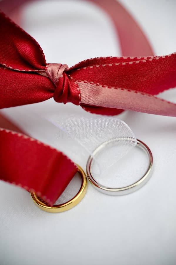 Anelli di cerimonia nuziale e un nastro rosso fotografia stock libera da diritti Anelli di cerimonia nuziale e un nastro rosso fotografia stock libera da diritti