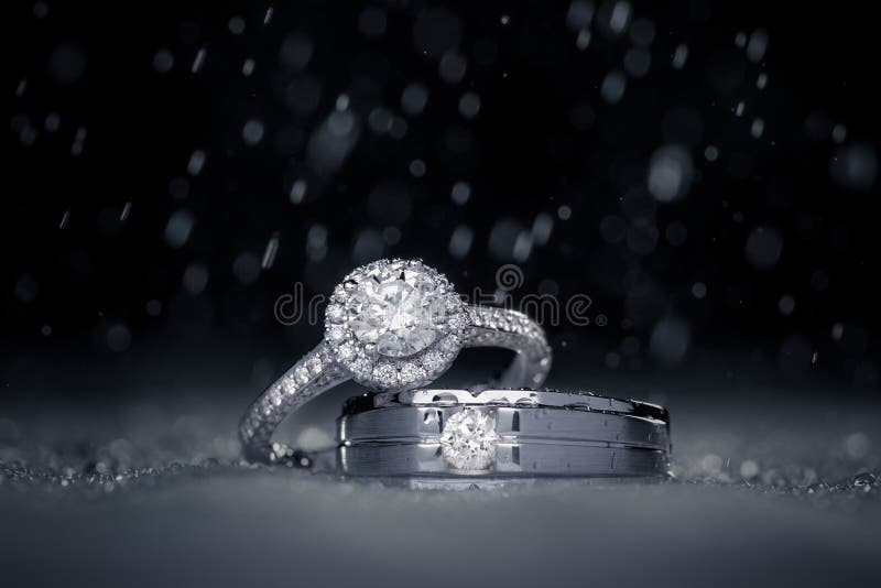 Anelli di diamante di impegno di nozze con le gocce di acqua fotografia stock Anelli di diamante di impegno di nozze con le gocce di acqua fotografia stock