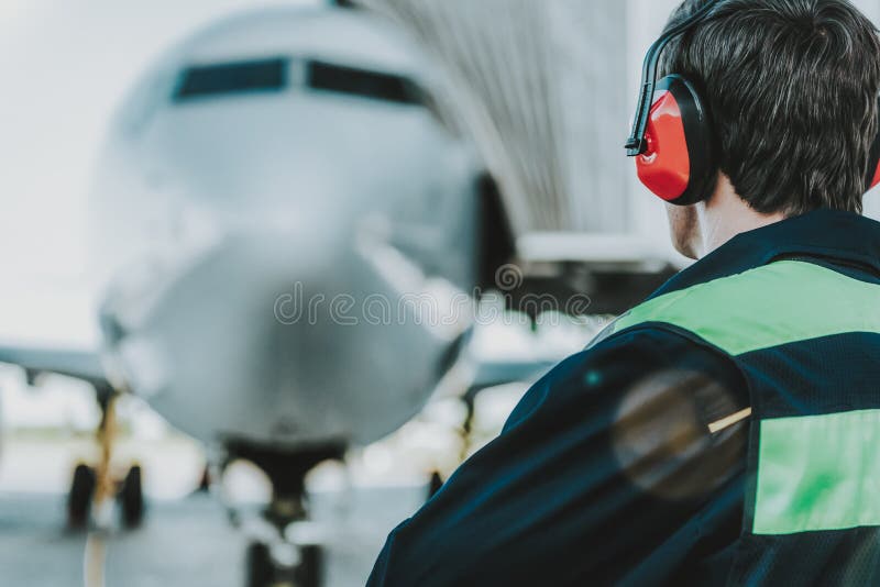 Angajat cu căști roșii care lucrează pe aerodrom stock photos