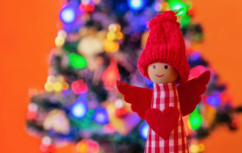 Angel in a Red Knitted Hat on the Background of the Christmas Tree. New