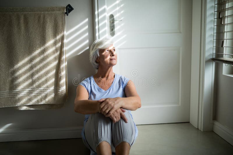 Angespannte ältere Frau, die durch Fenster im Schlafzimmer schaut lizenzfreies stockbild Angespannte ältere Frau, die durch Fenster im Schlafzimmer schaut lizenzfreies stockbild